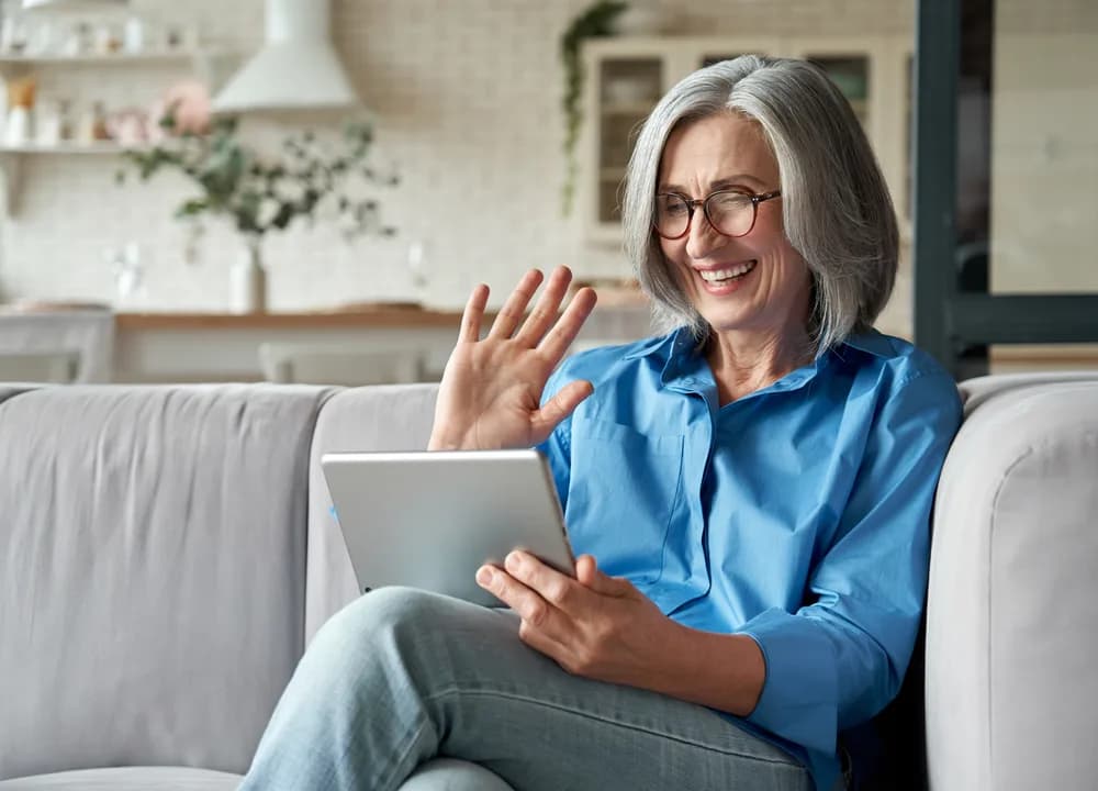 Senior woman using smartphone and laptop for tech support